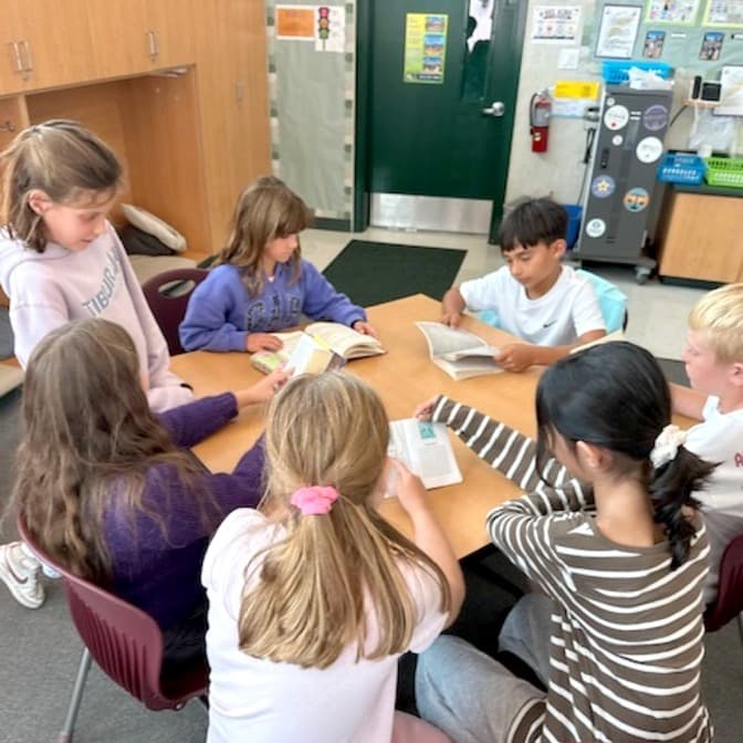 Students reading together around a classroom table.
